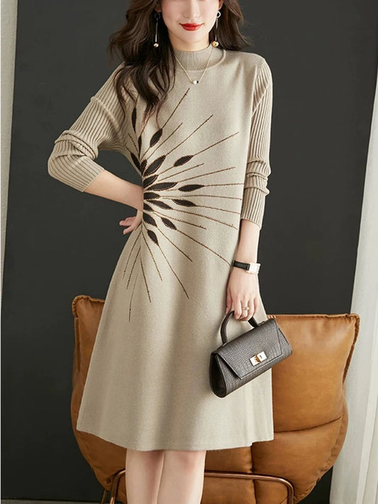 Woman wearing a beige dress with a black abstract pattern, holding a black handbag against a dark background.