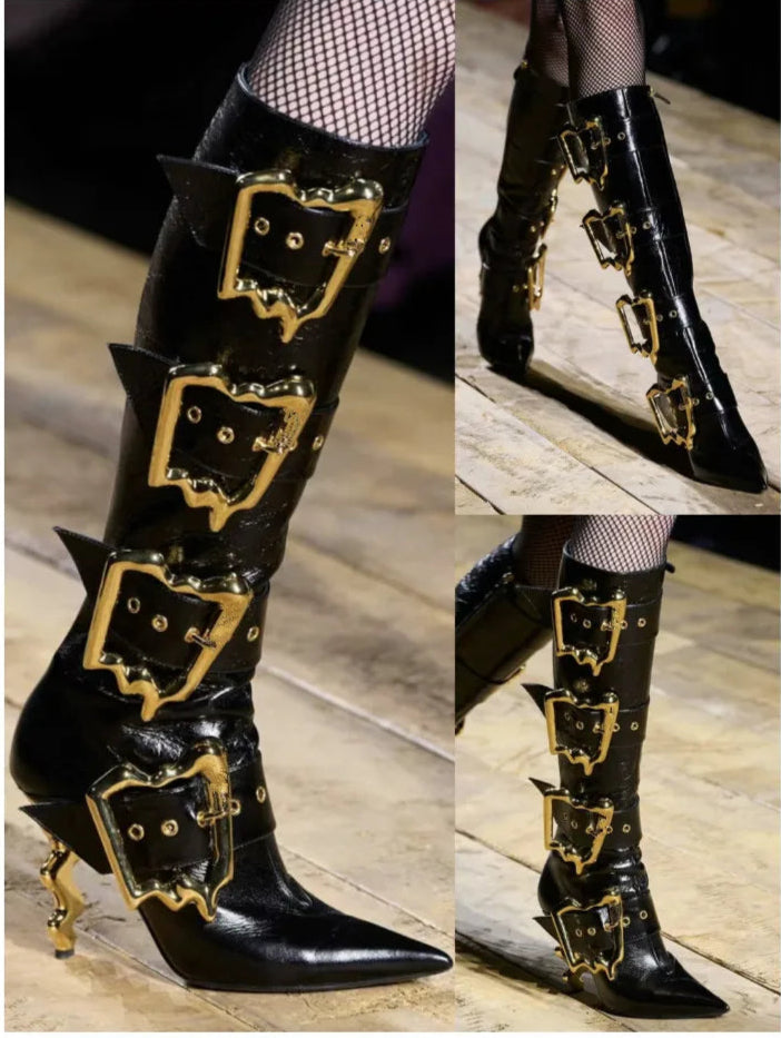 Black knee-high boots with gold buckles on a wooden floor.