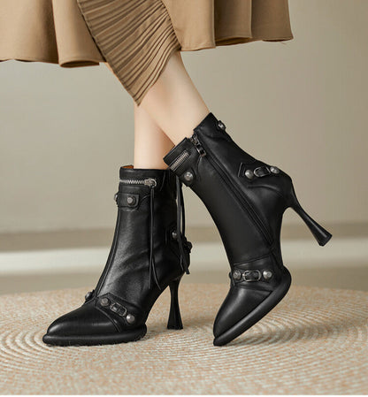 Black high-heeled boots worn with a beige skirt on a neutral background