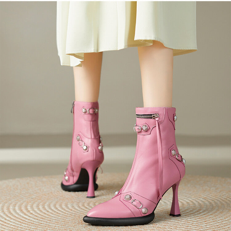 Pink high-heeled boots with decorative elements worn by a person in a light-colored skirt.