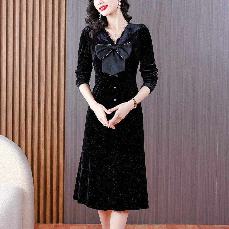 Woman wearing a black dress with a large bow tie in an indoor setting