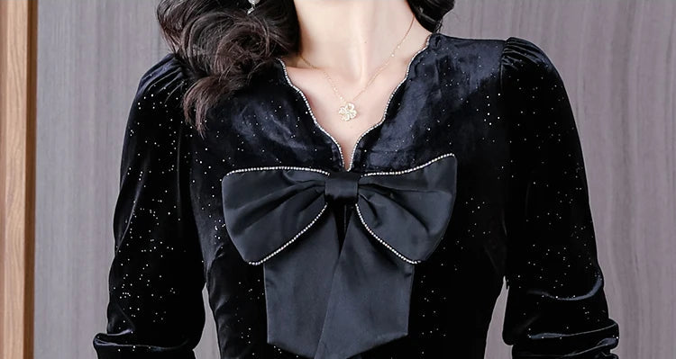 Black velvet blouse with a large bow detail on a neutral background
