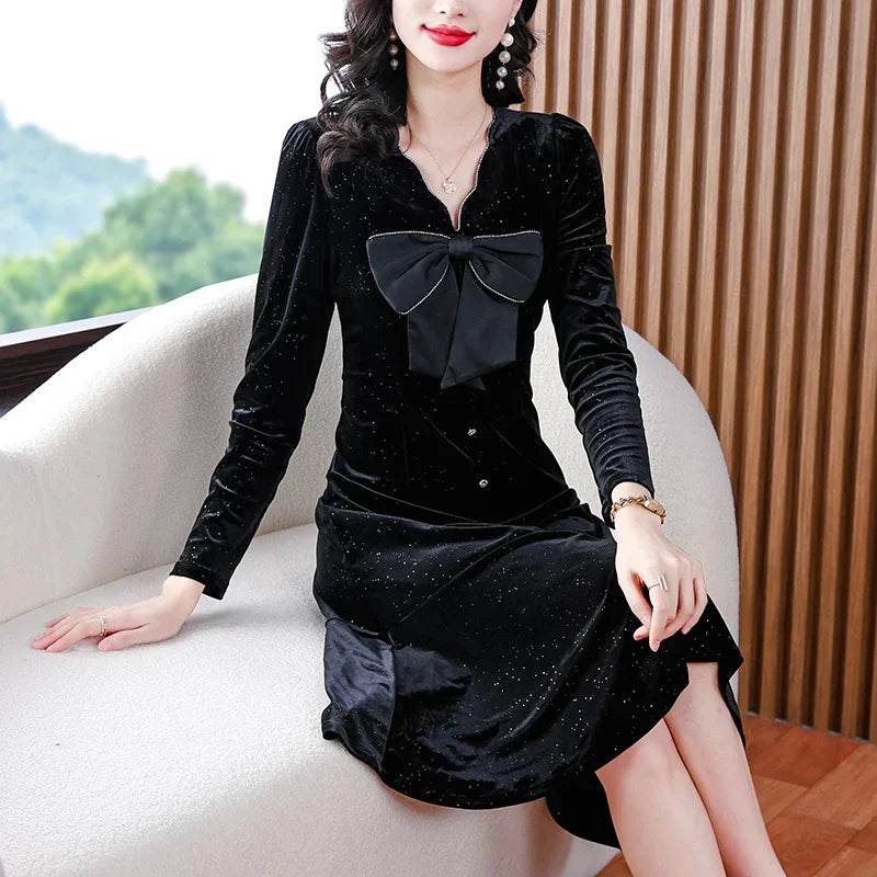 Woman wearing a black dress with a bow sitting on a white couch.