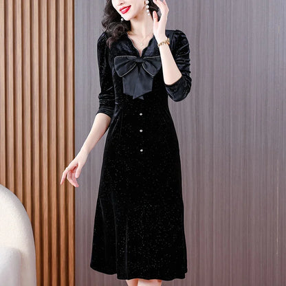 Woman wearing a black dress with a bow detail against a neutral background