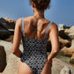 Woman wearing black abstract print cutout one-piece swimsuit